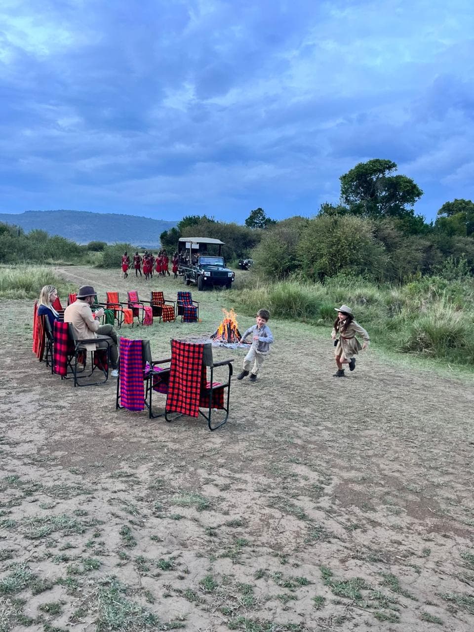 A family relaxing by the campfire at a Maasai Mara safari camp